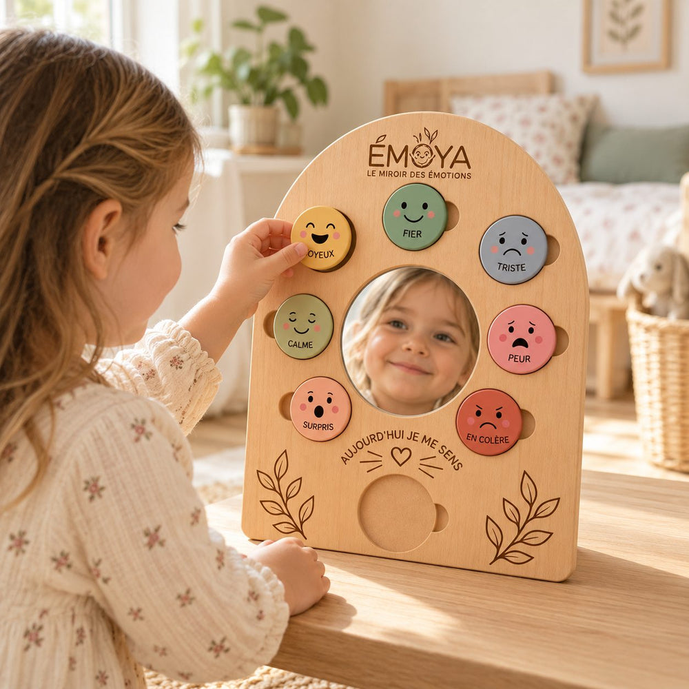 Un enfant d'environ 4 ans pose un jeton jaune sur le miroir des émotions ÉMOYA, installé sur une table dans une chambre lumineuse